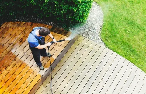 Pressure washing vs soft washing comparison shown on a wooden deck with dirty and clean sections side by side.